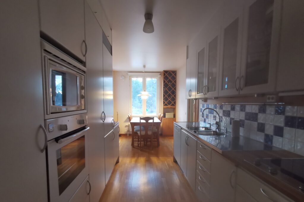 Kök och matplats före homestyling med träbord, stolar, vinförvaring och personliga detaljer.