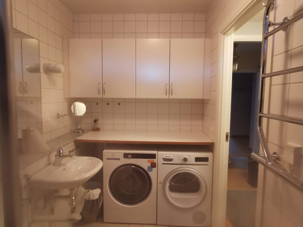 Badrum före homestyling med blå kakelvägg, vita plattor och enkel inredning